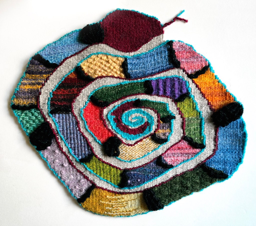 Colorful knitted spiral pattern made of various textured yarns.